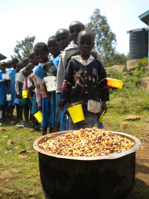 children lined up for lunch of maize and beans